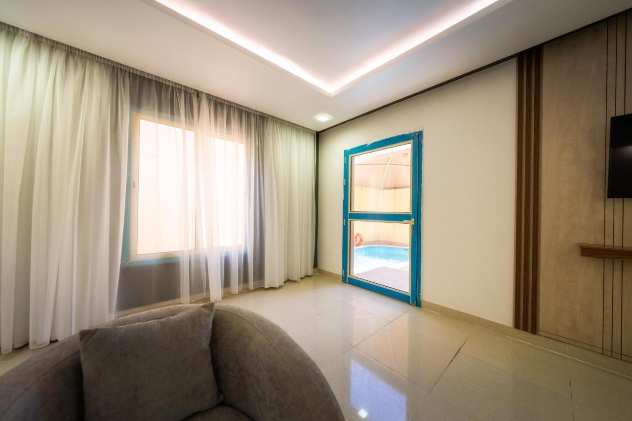 Mirada Gold Jizan - Resort & Private Pools Экстерьер фото The photo shows a modern interior space that appears to be a room in a home or a building. There is a large window with sheer curtains letting in natural light, which contributes to a bright and airy atmosphere. On one side of the room, there is a sl